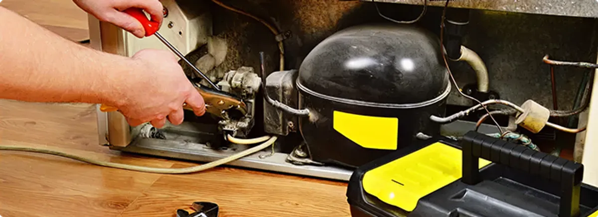 Refrigerator repair technician fixing the compressor and wiring in New Carlisle, IN
