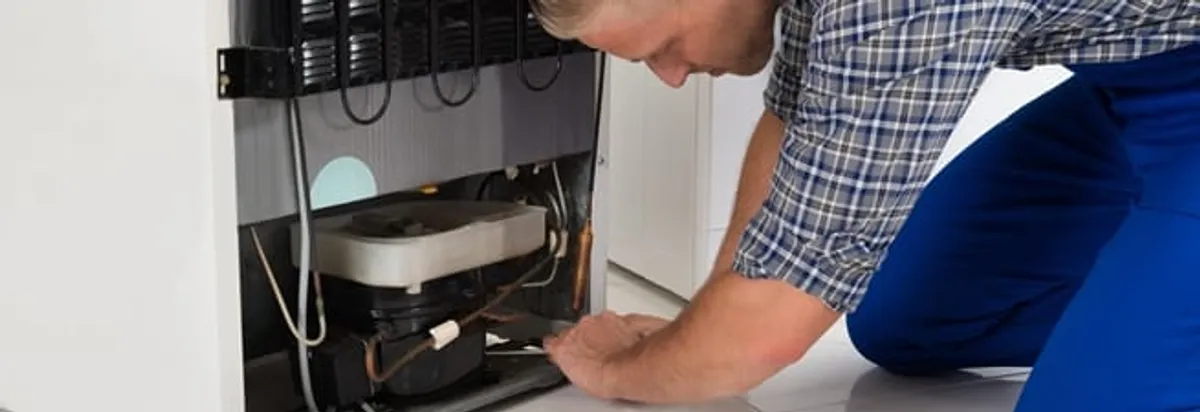 Refrigerator repair technician servicing the compressor and condenser area in South Bend, IN